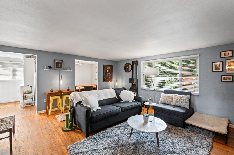 A living room with a couch , table , chairs and a rug.
