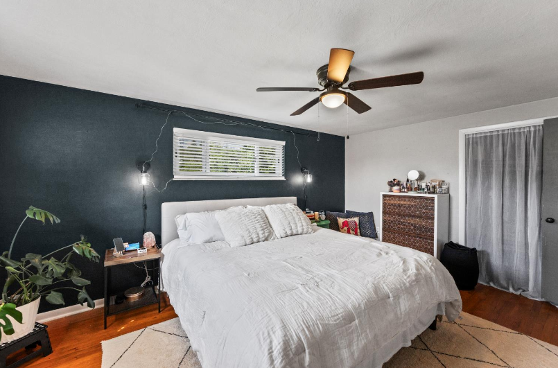 A bedroom with a large bed and a ceiling fan.