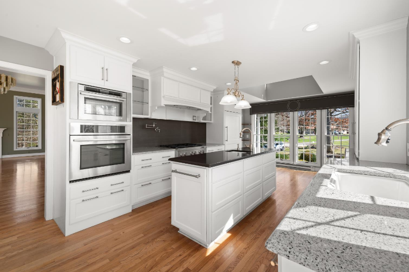 A kitchen with white cabinets , granite counter tops , and stainless steel appliances.