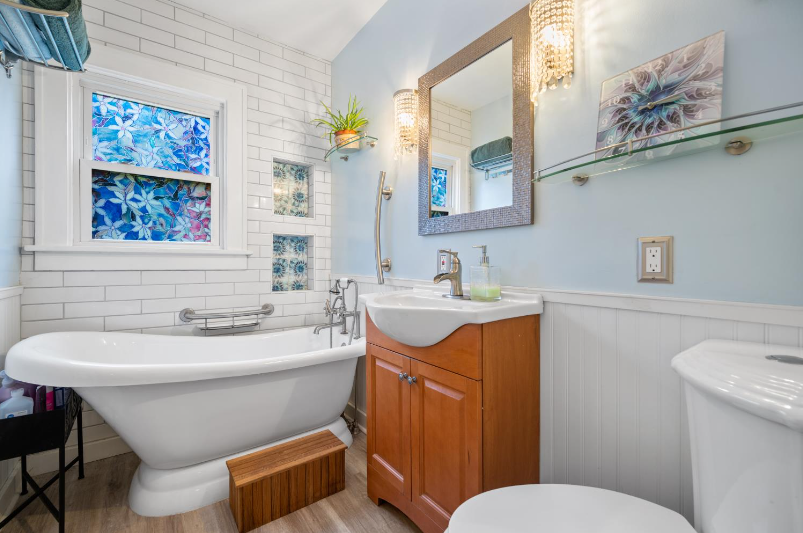 A bathroom with a tub , sink , toilet and mirror.