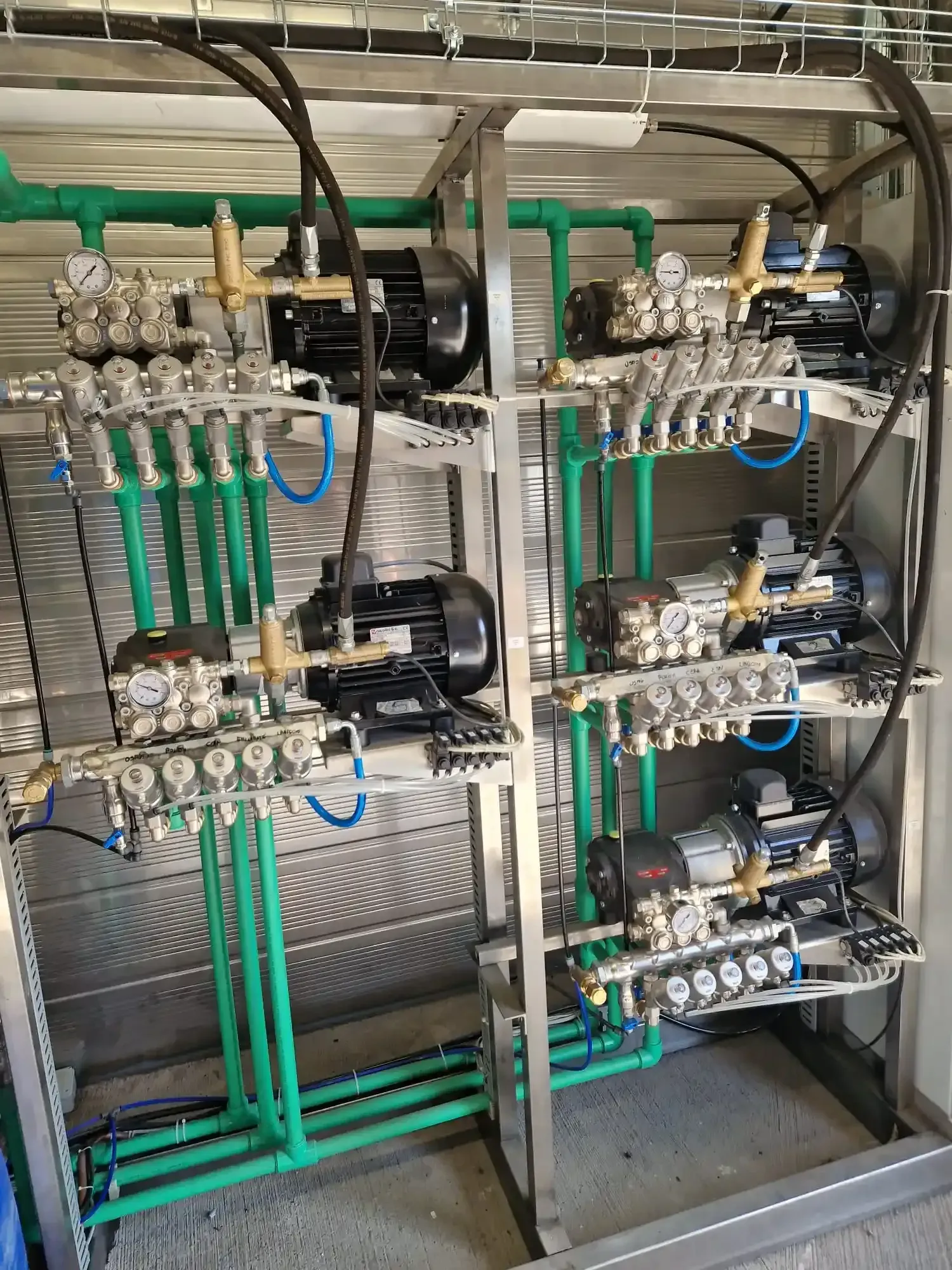 Sistema di pompaggio dell'acqua industriale verde e argento con manometri.