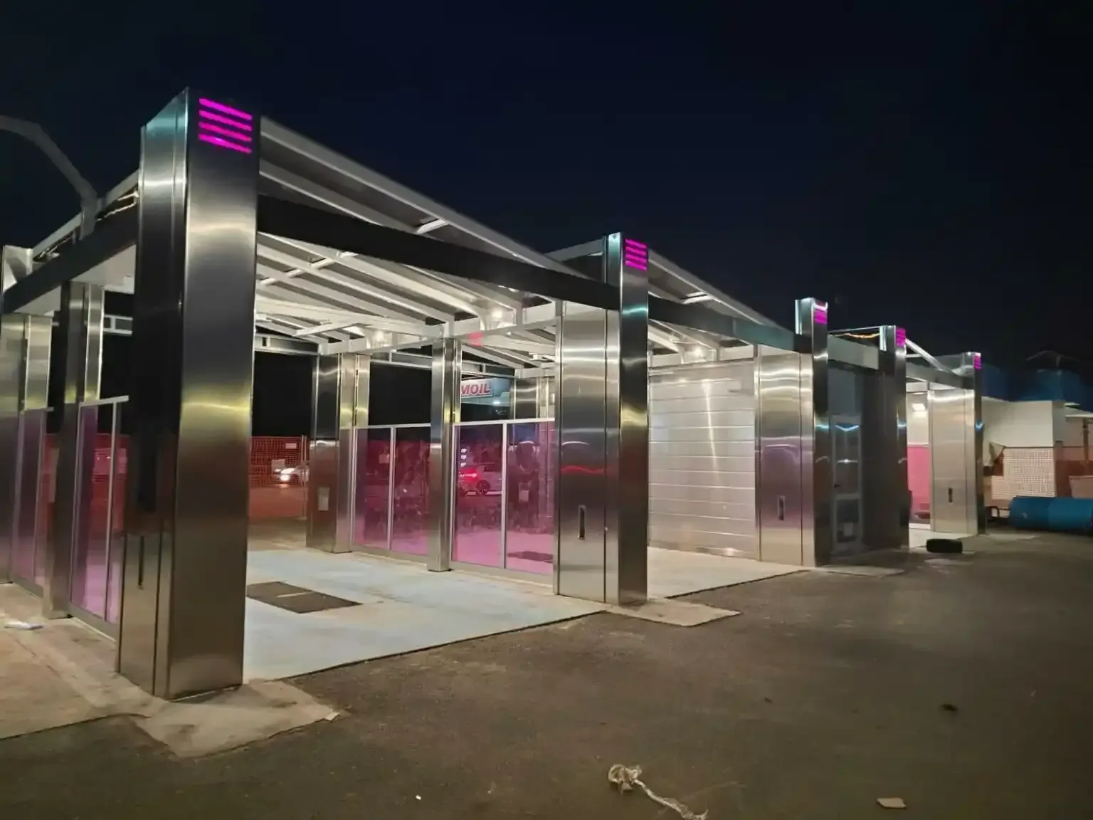 Moderni autolavaggi in acciaio inox con illuminazione rosa di notte.
