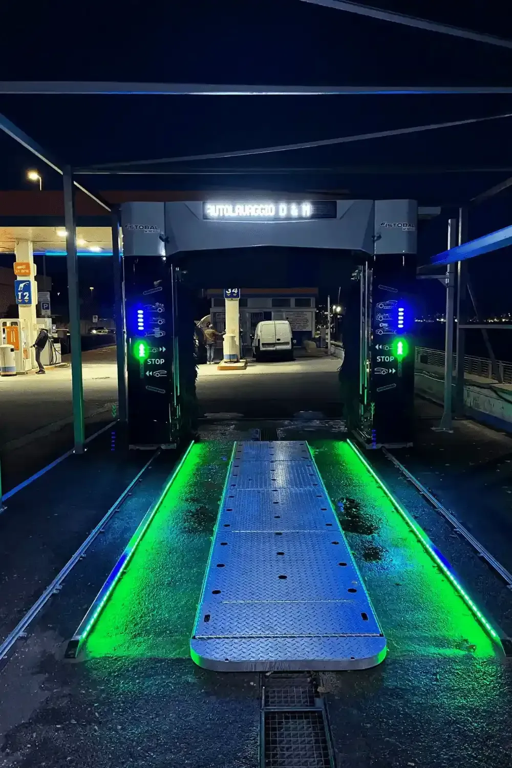 Ingresso dell'autolavaggio di notte, illuminato con luci verdi e blu.