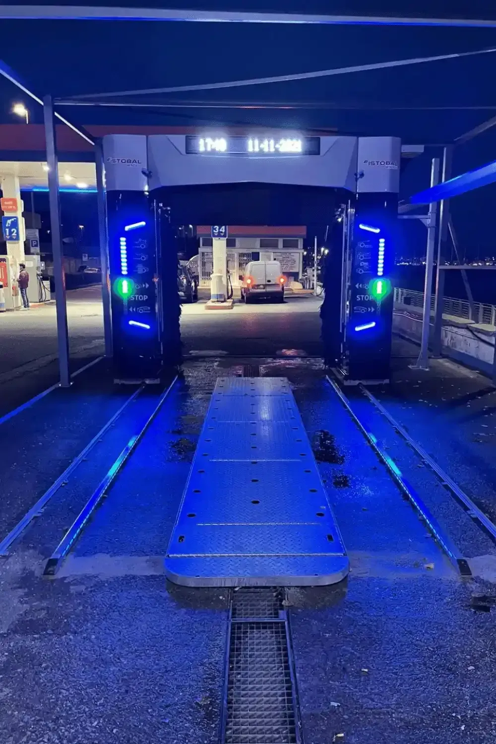 Area di lavaggio auto di notte, illuminata con luci blu e verdi.