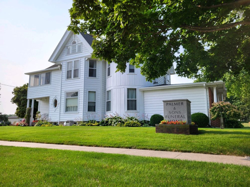 A white house with a lush green lawn in front of it