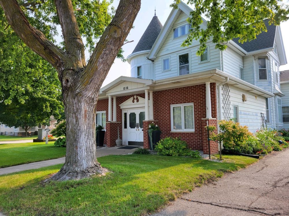 A large brick house with a tree in front of it.
