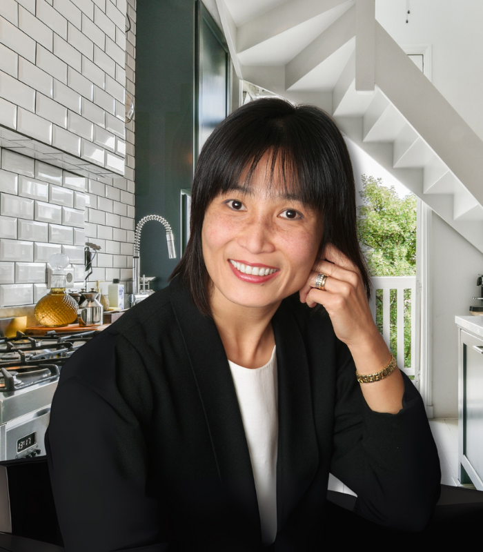 A woman in a black jacket is smiling in a kitchen