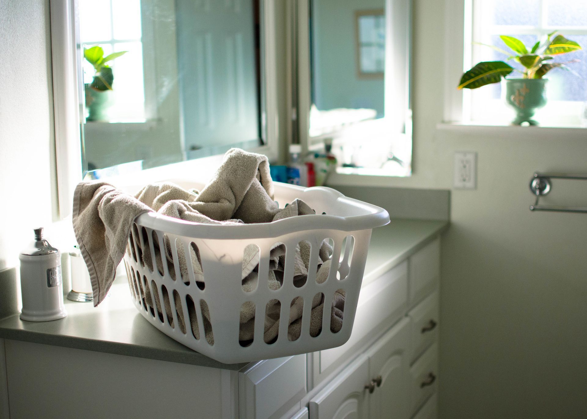 A laundry basket filled with towels sits on a bathroom counter.