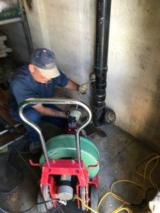 A man is using a machine to clean a pipe.