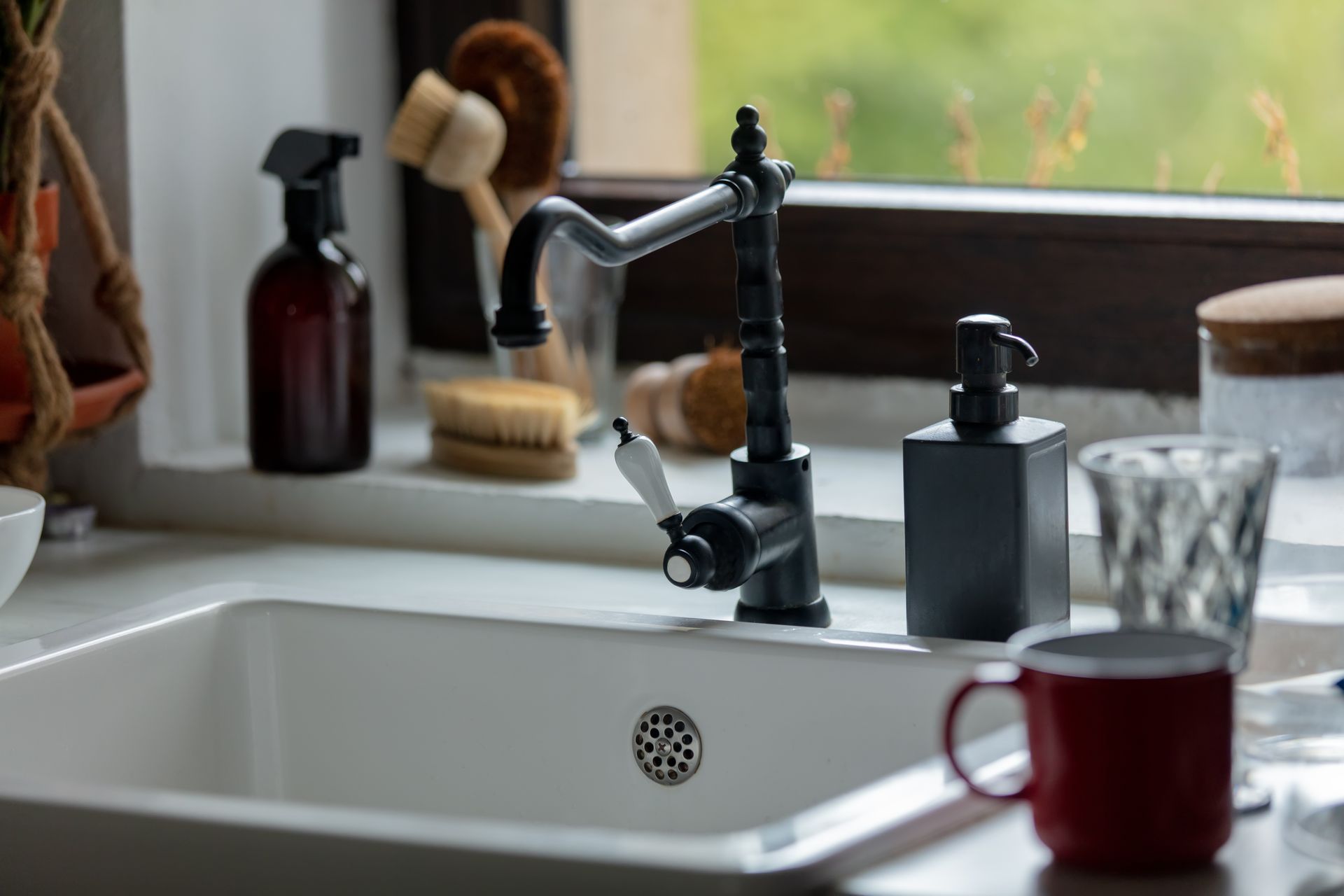 A kitchen sink with a faucet and a cup on the counter.
