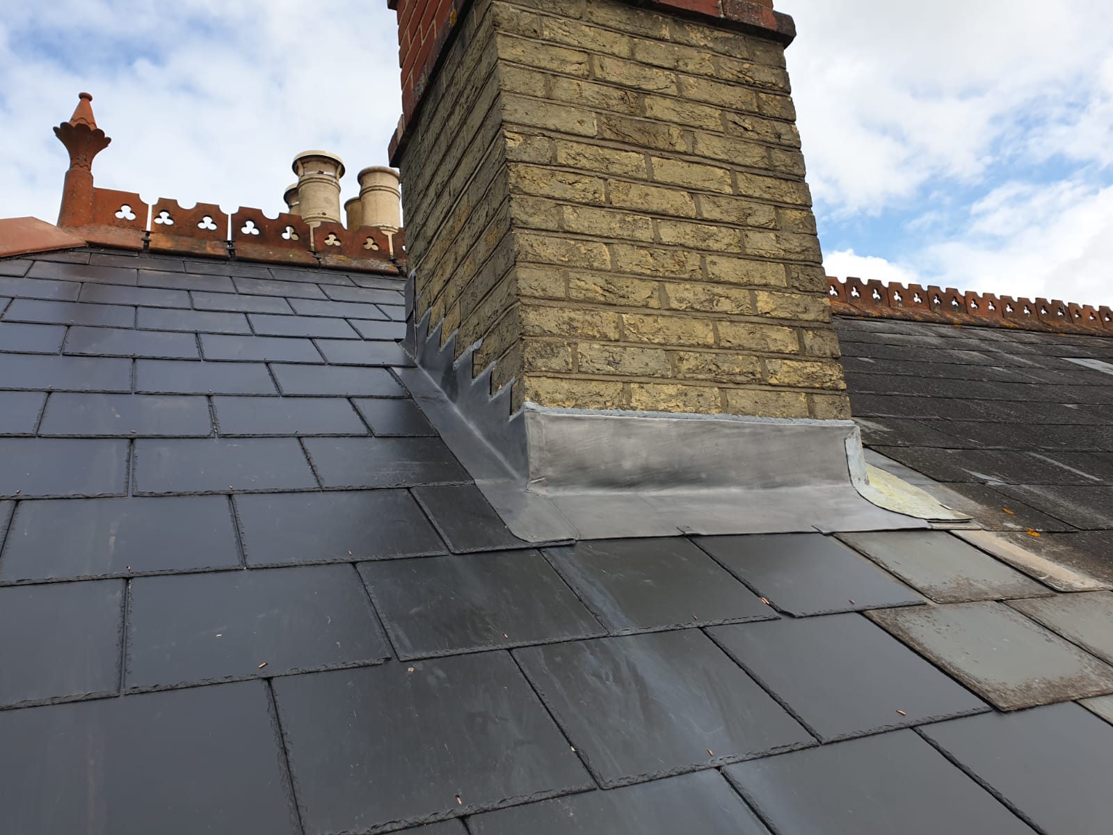 A chimney on top of a roof with a slate roof.