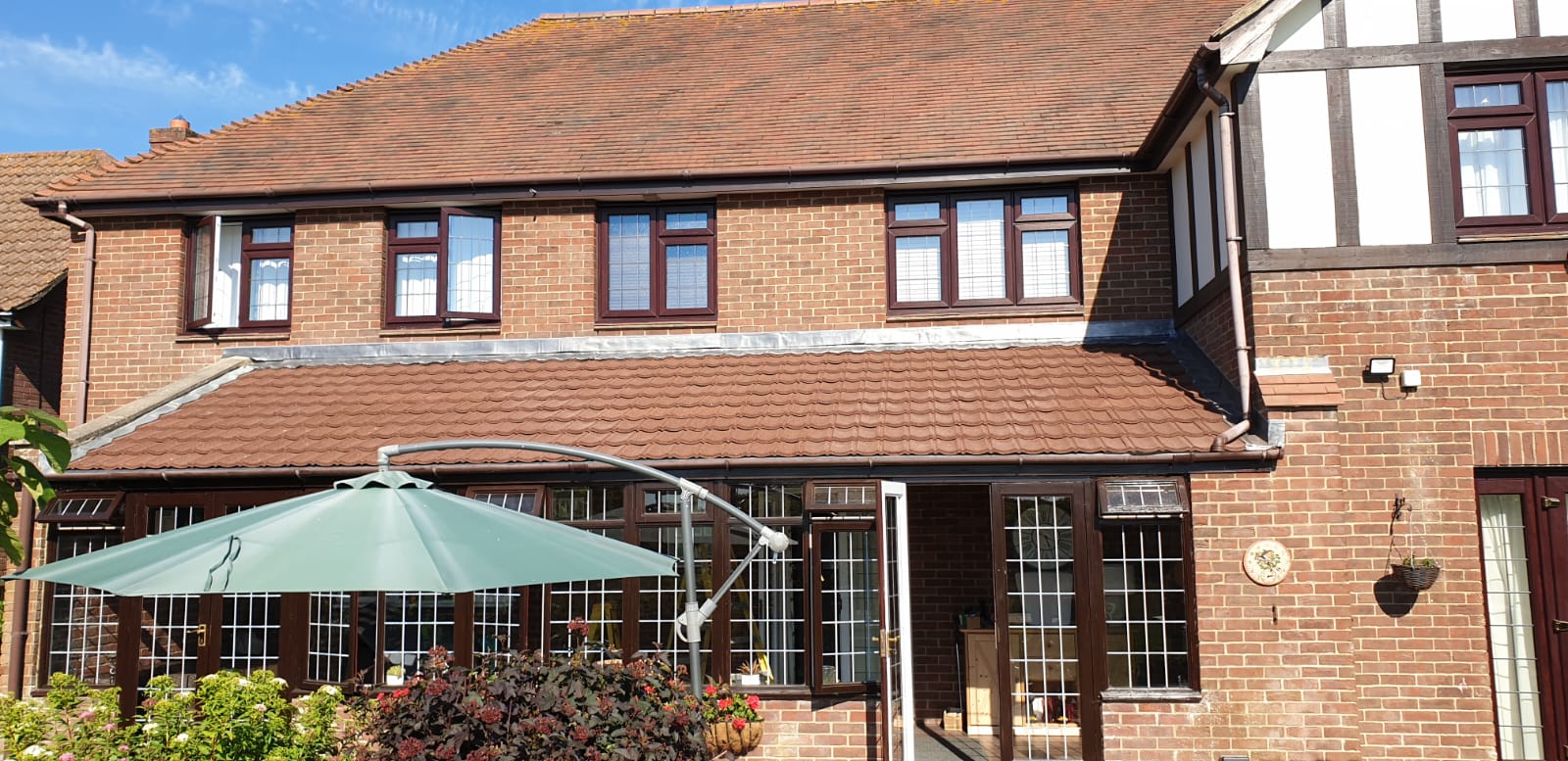 A large brick house with a green umbrella in front of it.