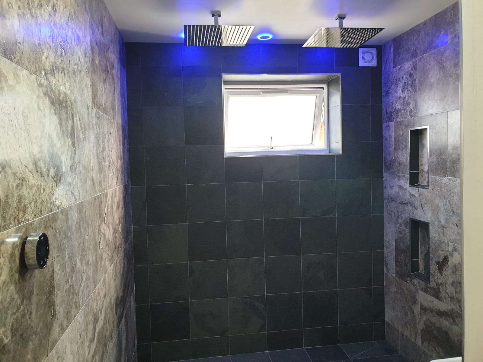 A bathroom with two shower heads and a window.