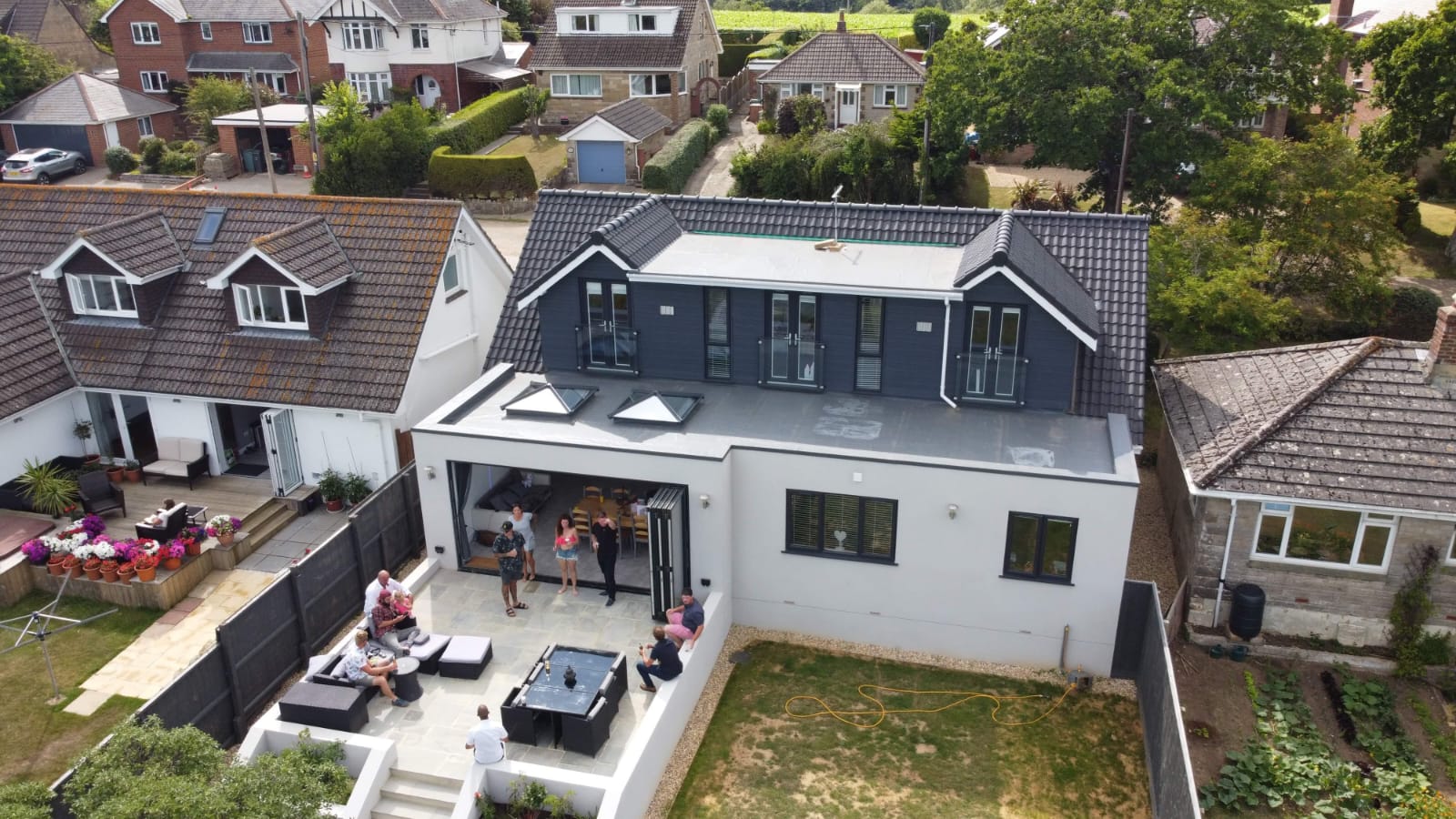 A group of people are sitting on a patio in front of a large house.