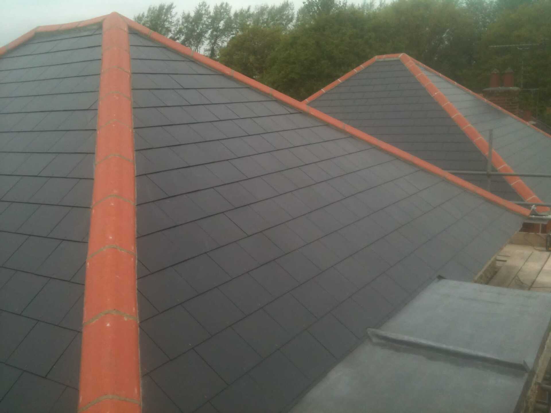 A roof with a red trim and a few trees in the background