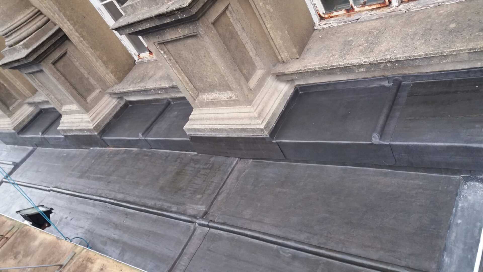 A close up of a building with a drain on the side of it.