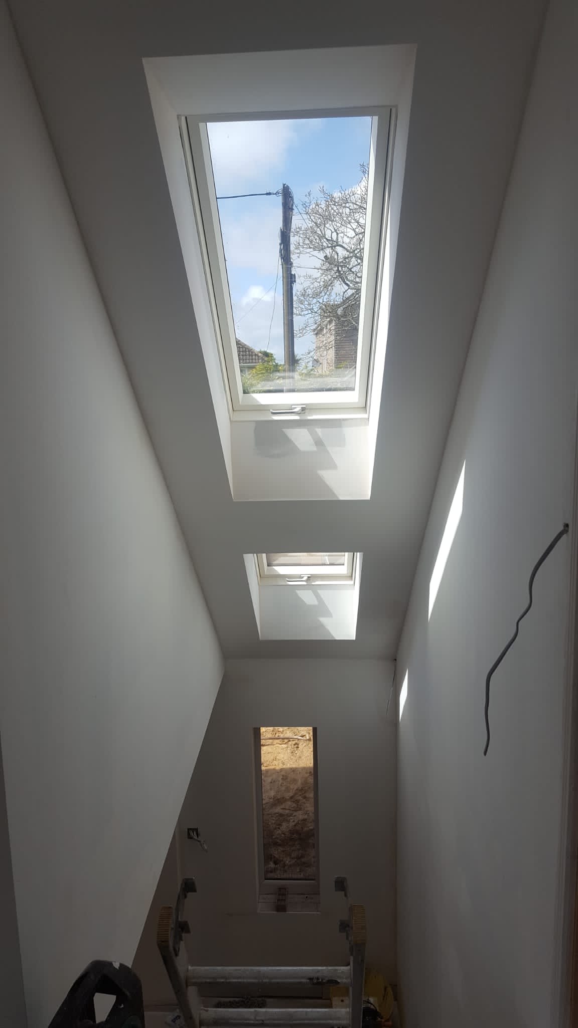 A narrow hallway with three skylights on the ceiling.