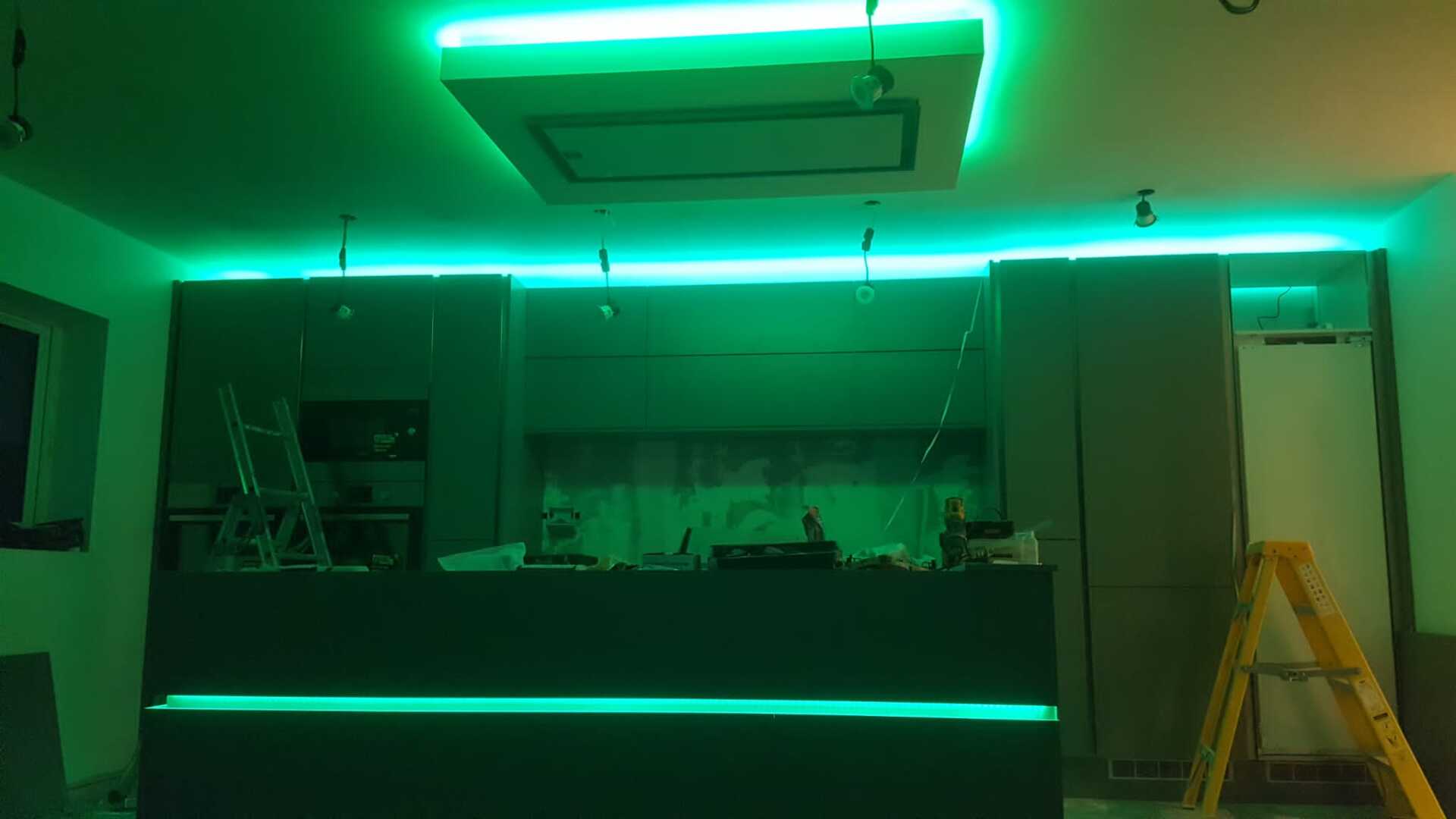 A kitchen with green lights on the ceiling and a ladder.