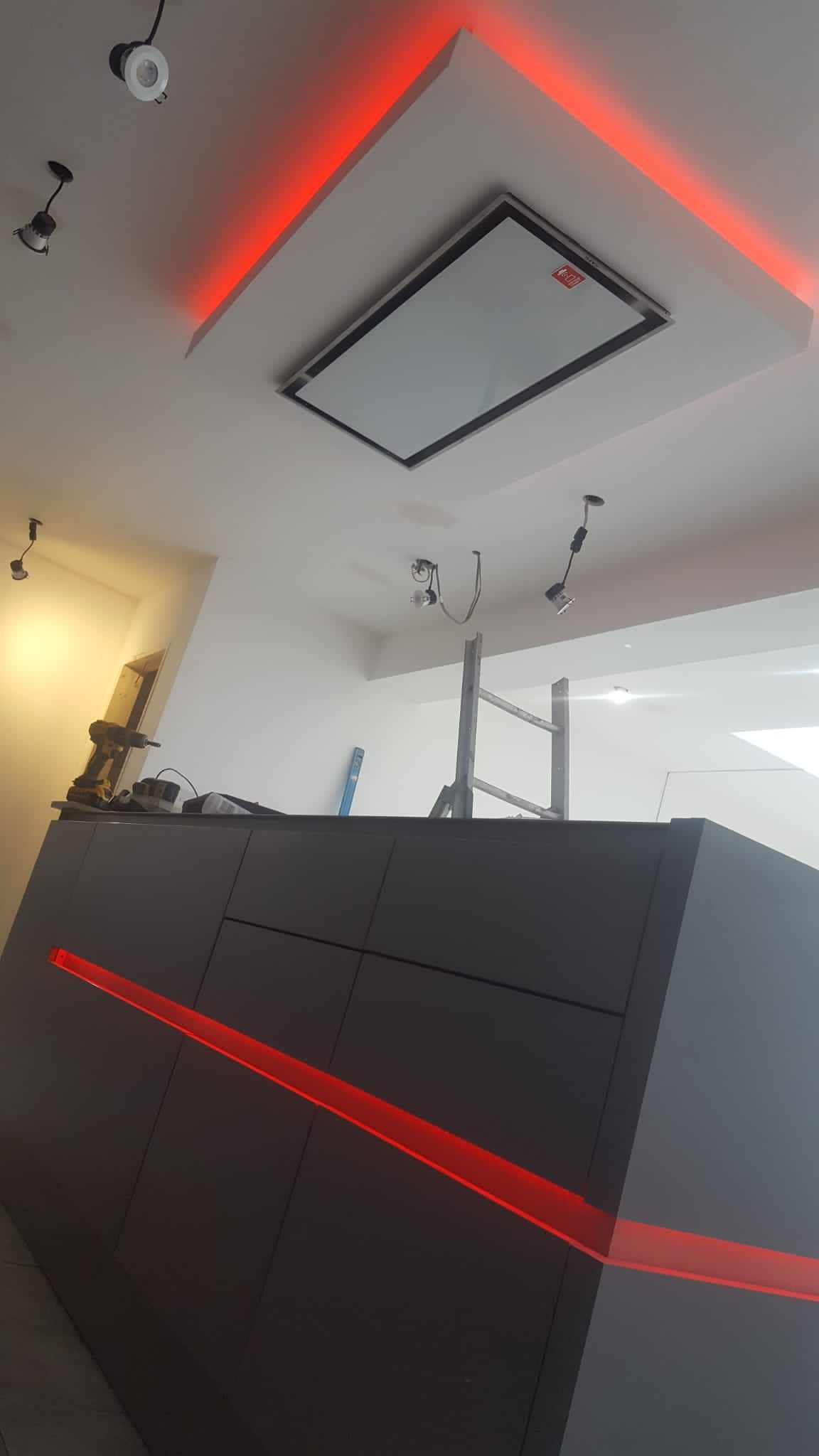 A kitchen with a ceiling fan and red lights on the ceiling.