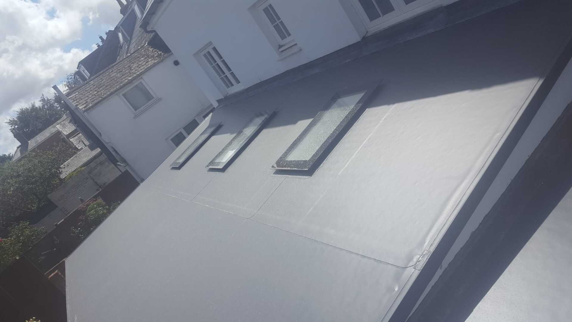 The roof of a house with three skylights on it.