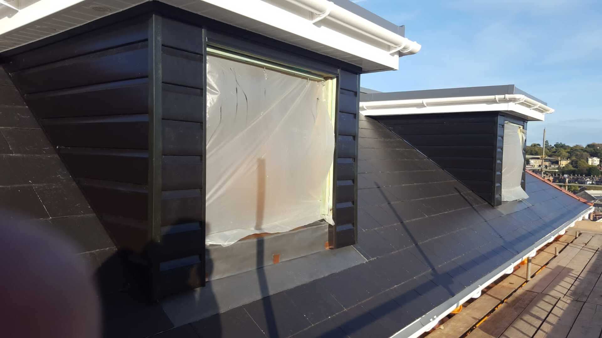 A roof with a window and a shadow of a person on it.