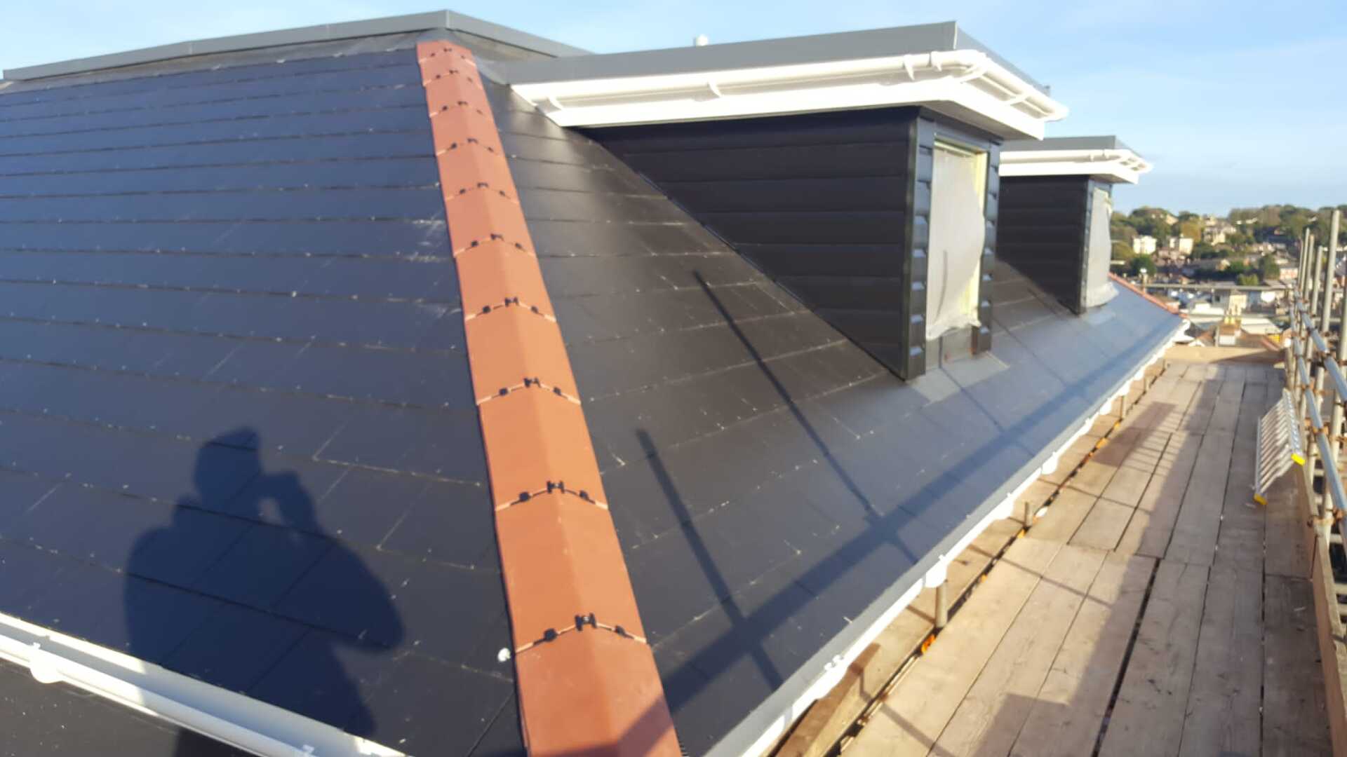A shadow of a person is cast on the roof of a building