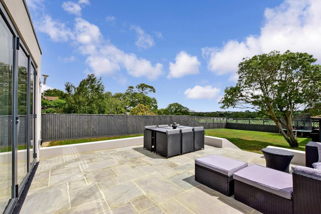 A patio with a table and chairs and a fence in the background.