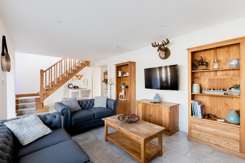 A living room with a couch , coffee table , television and stairs.