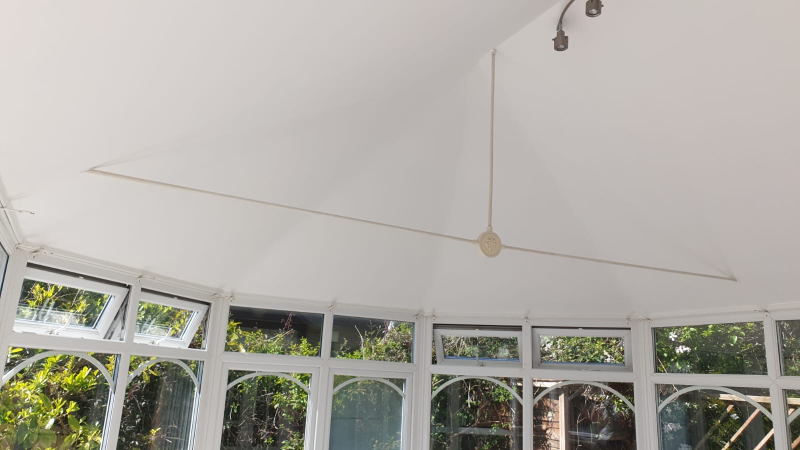 A room with a lot of windows and a ceiling fan.