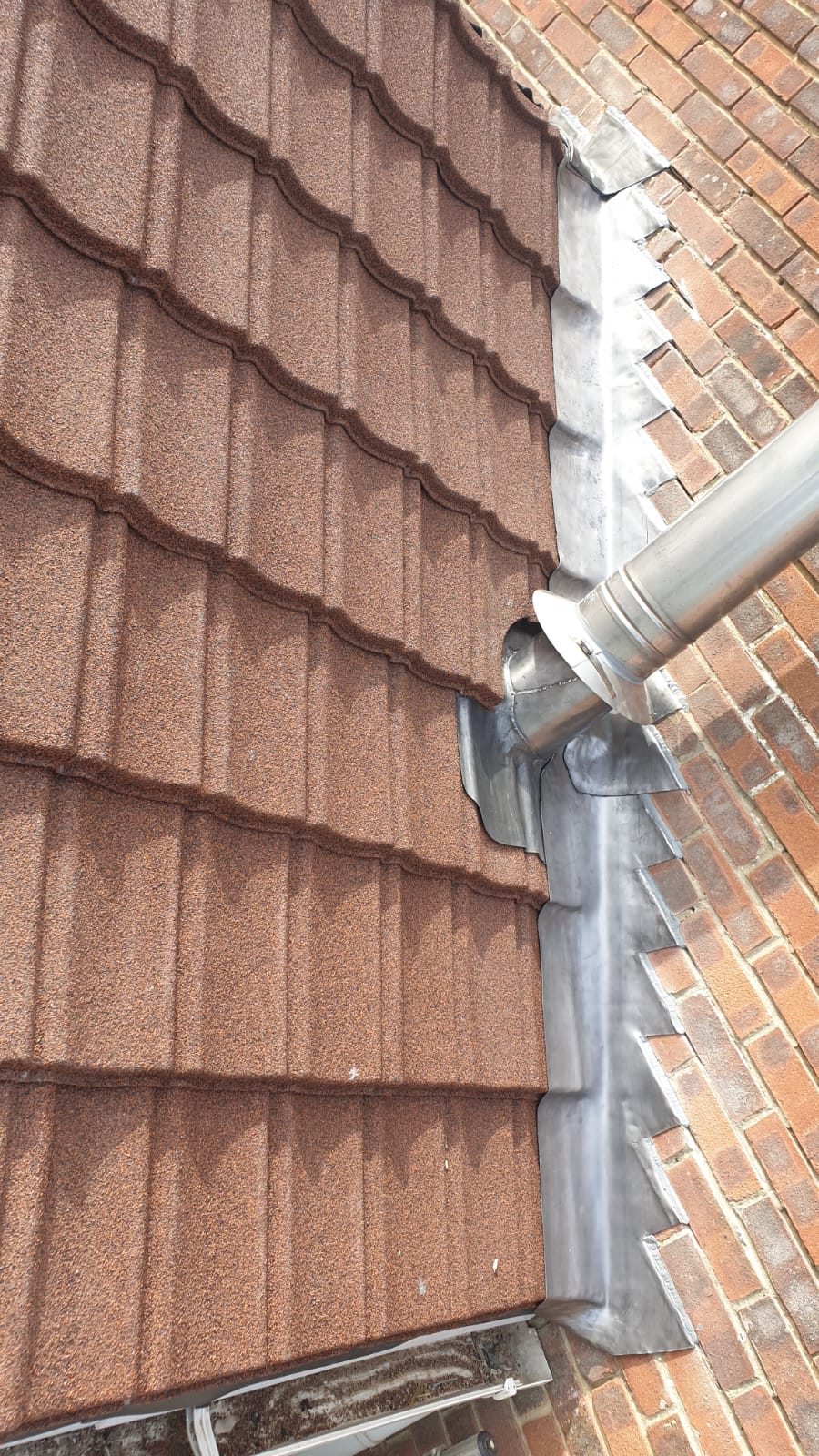 A close up of a gutter on the side of a brick building.