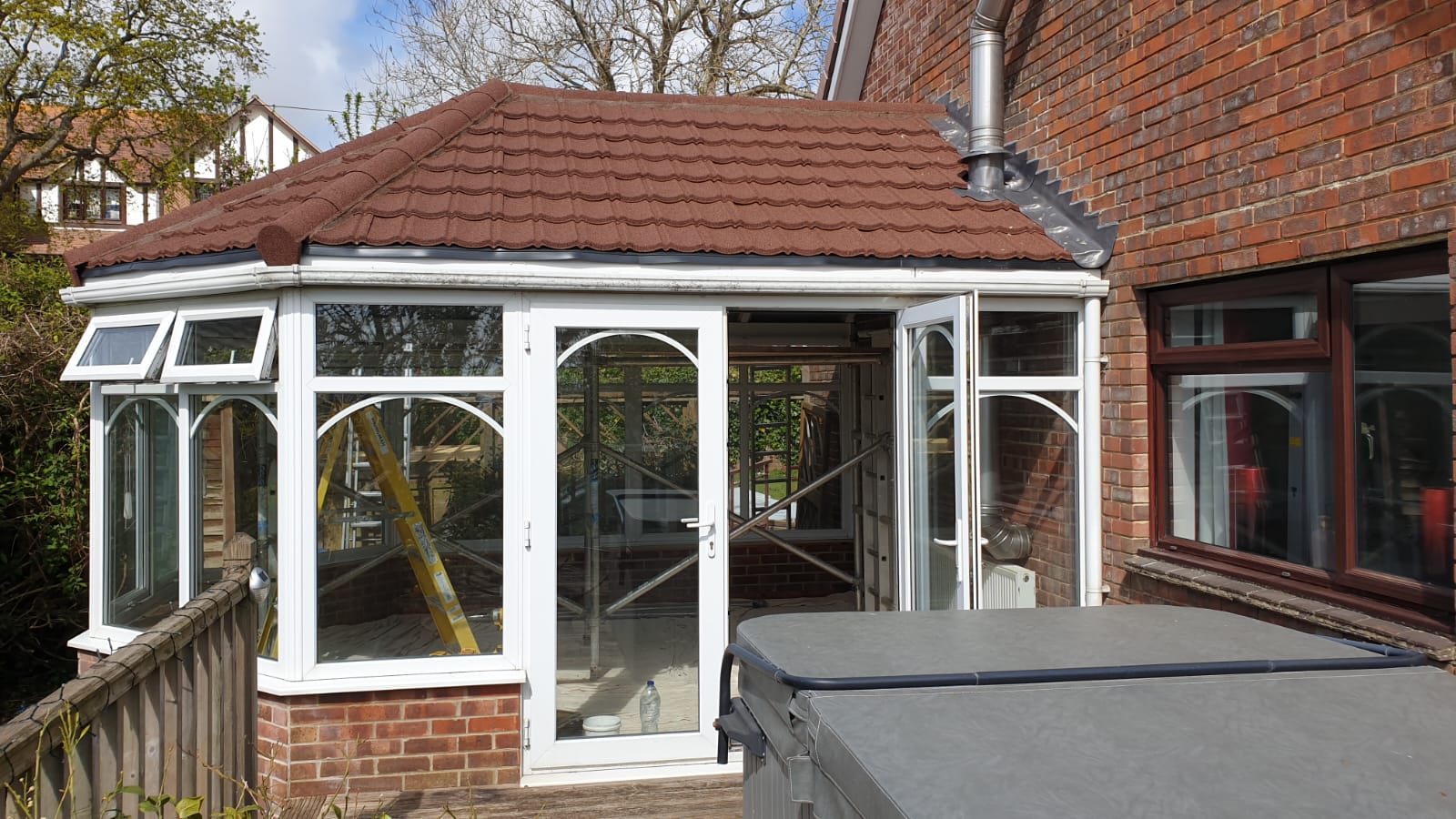 A conservatory is being built on the side of a brick house.
