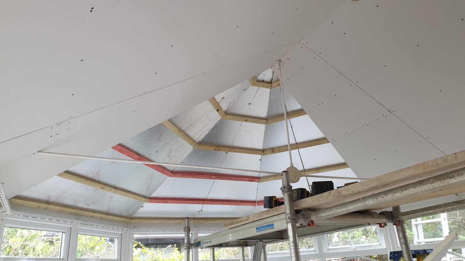 A room with a ceiling that is being built and a lot of windows.