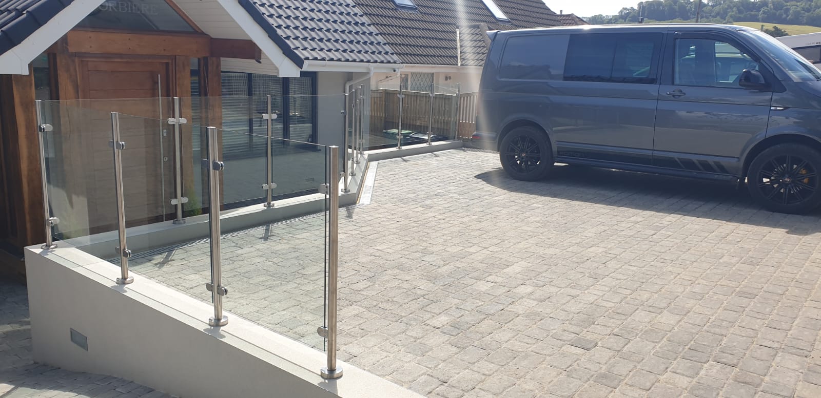 A van is parked in front of a house with a glass railing.