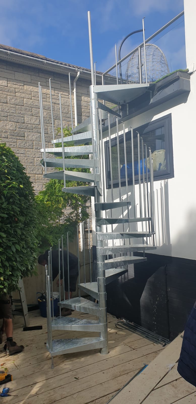 A spiral staircase is being built outside of a house.