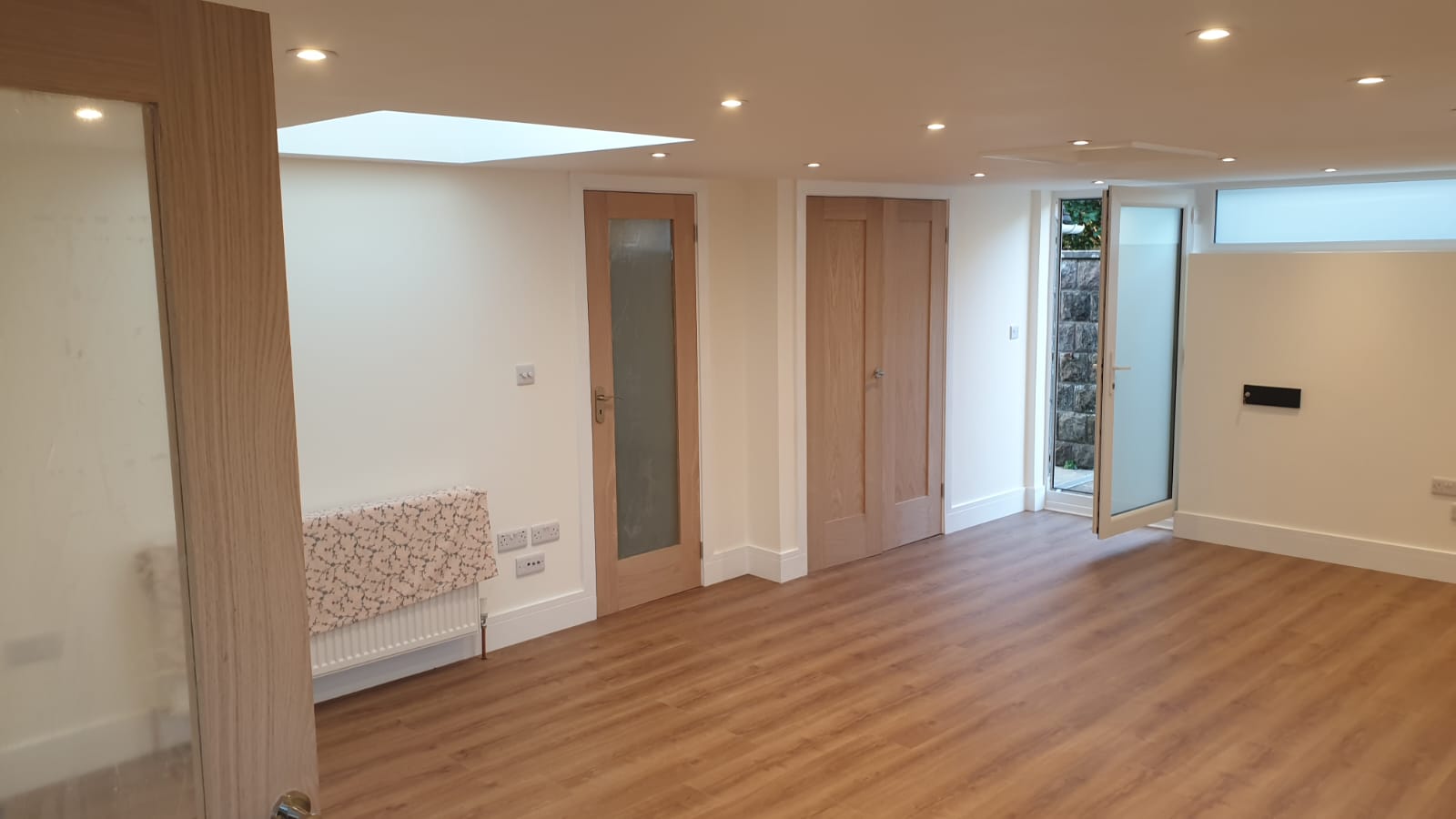 An empty living room with wooden floors and white walls.