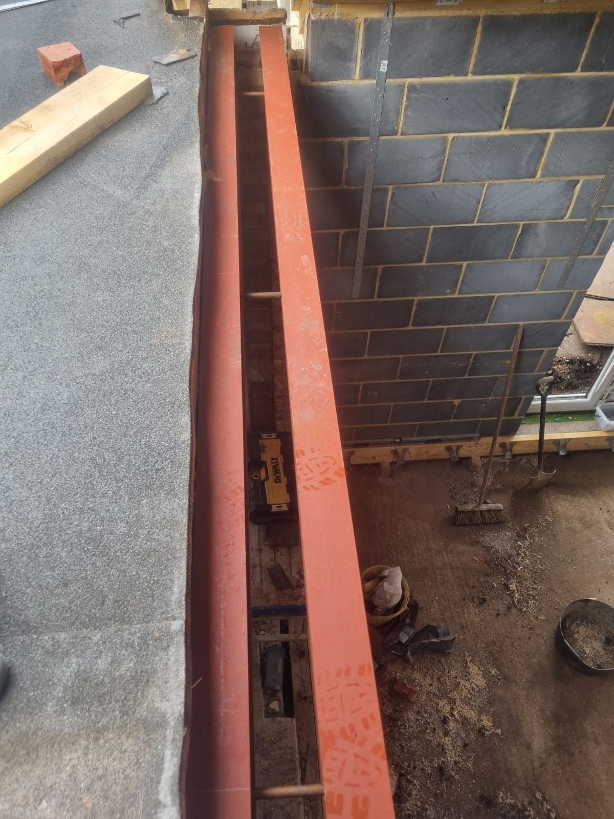 A red metal beam is being built into a brick wall.