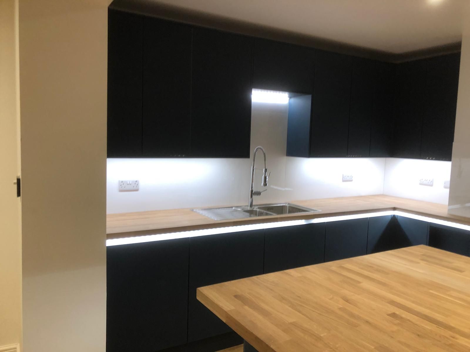 A kitchen with black cabinets and a wooden counter top