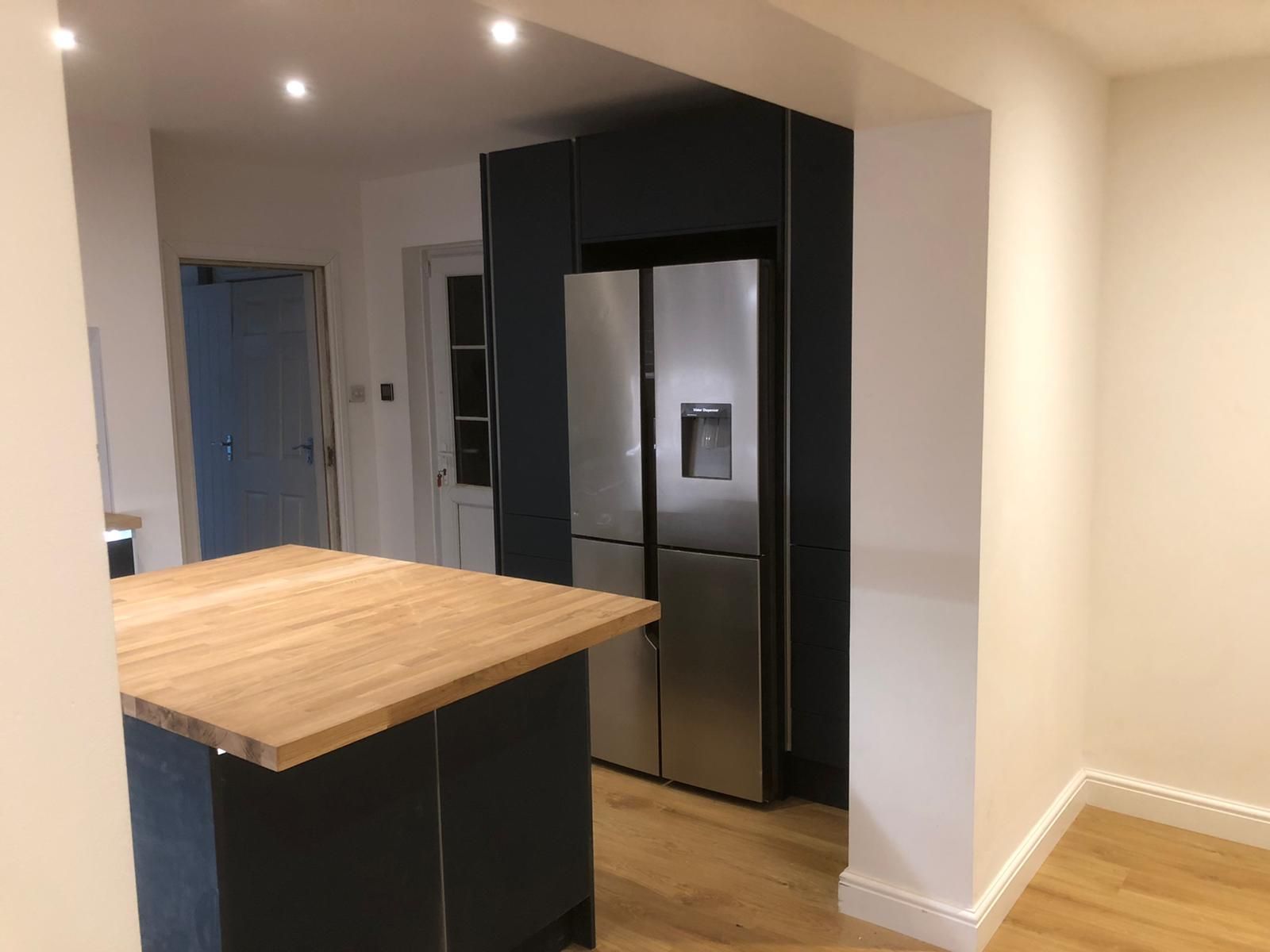 A kitchen with a stainless steel refrigerator and a wooden counter top.