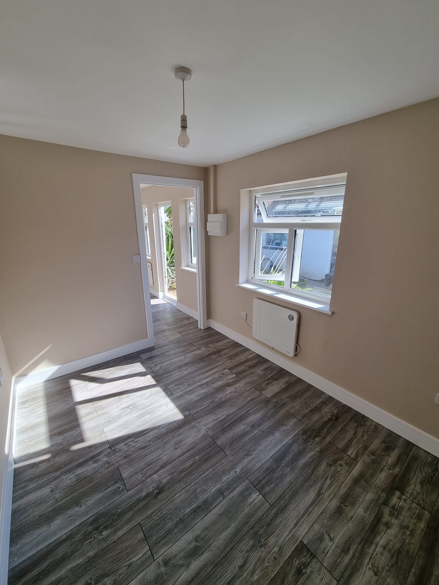 An empty room with hardwood floors and a window.