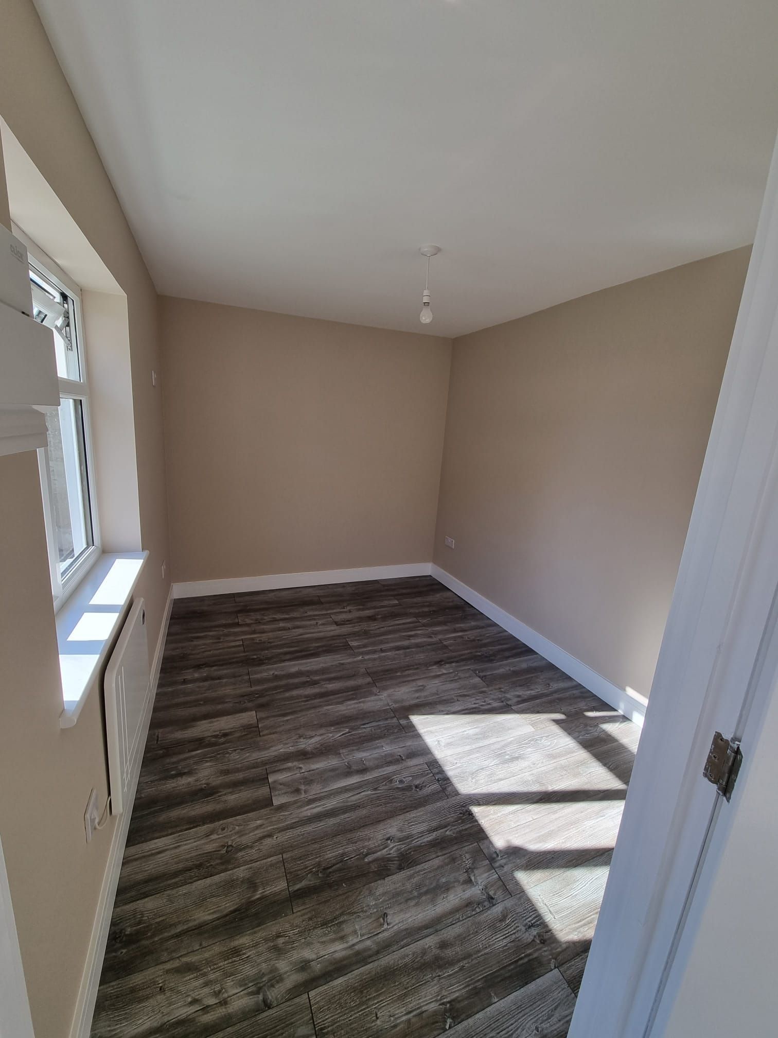 An empty room with a wooden floor and a window.