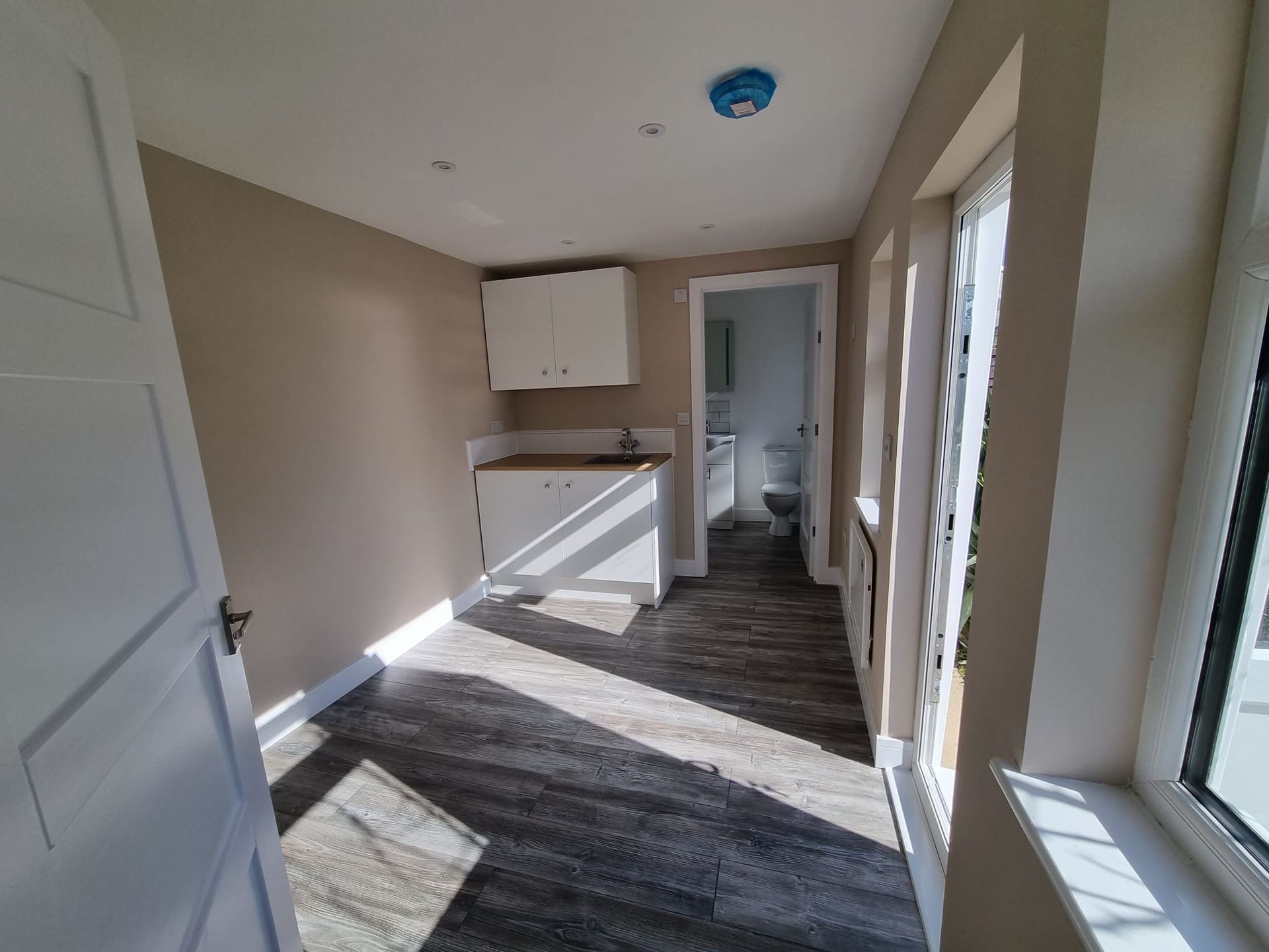 A room with a sink , toilet , cabinets and a window.