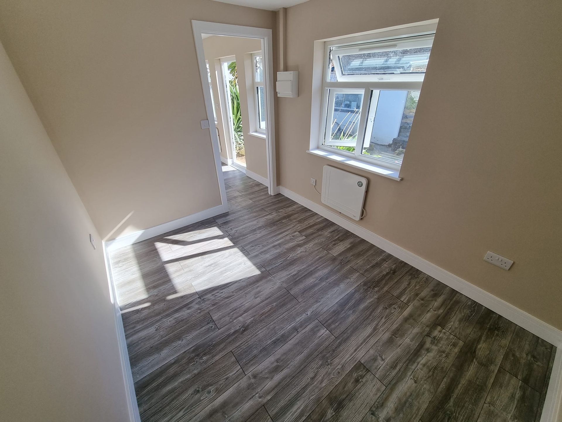An empty room with hardwood floors and a window.