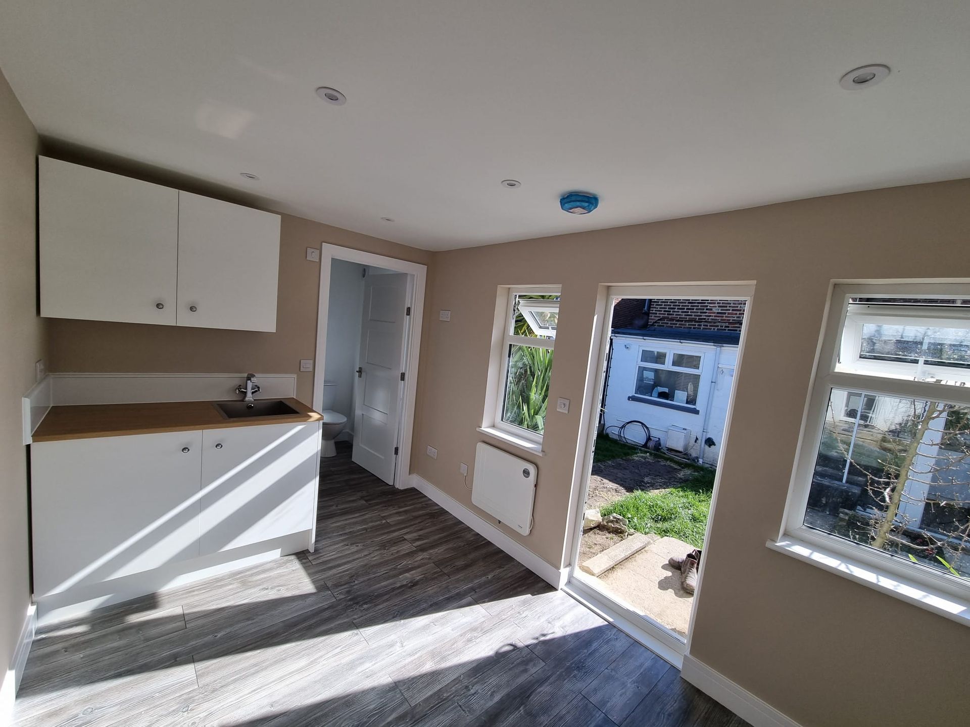 A kitchen with a sink , cabinets , and sliding glass doors.