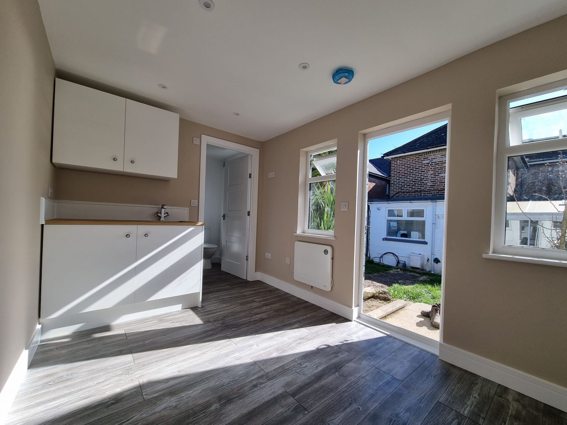 An empty room with a sink , cabinets , and windows.