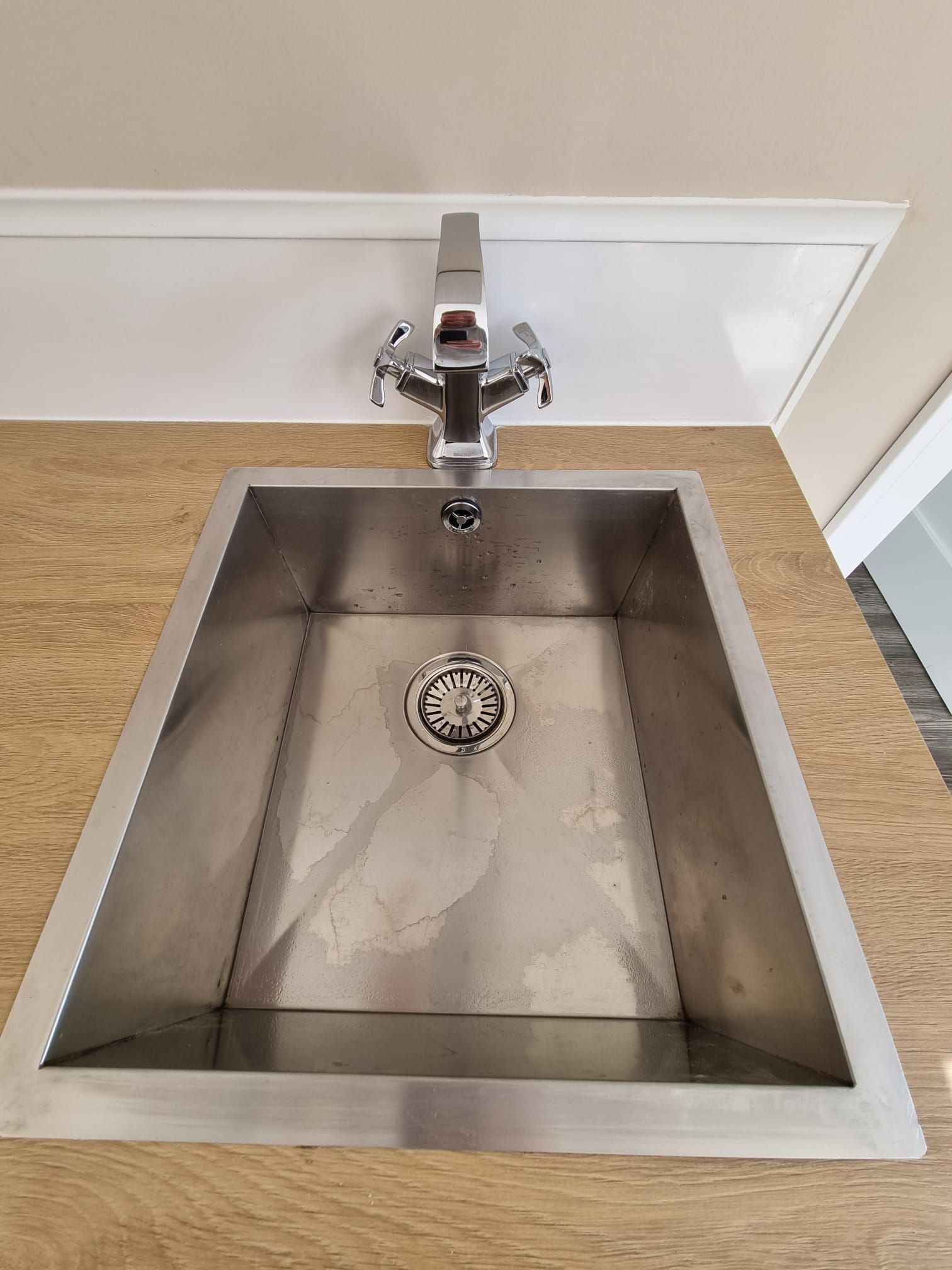 A stainless steel sink with a faucet in a kitchen.
