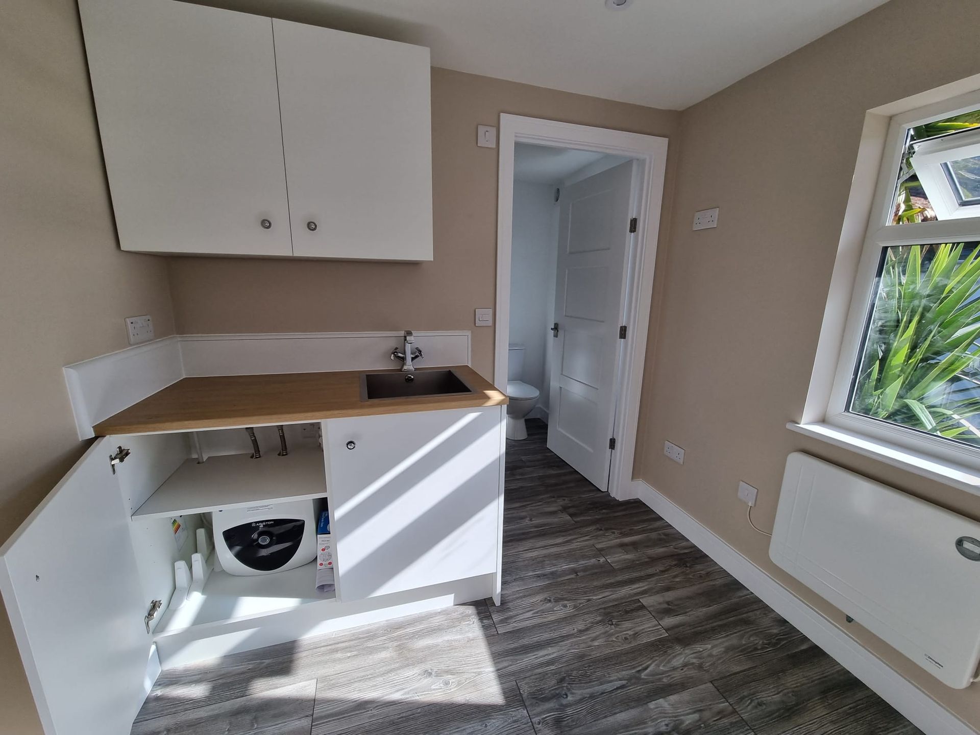 A kitchen with a sink , cabinets , and a window.