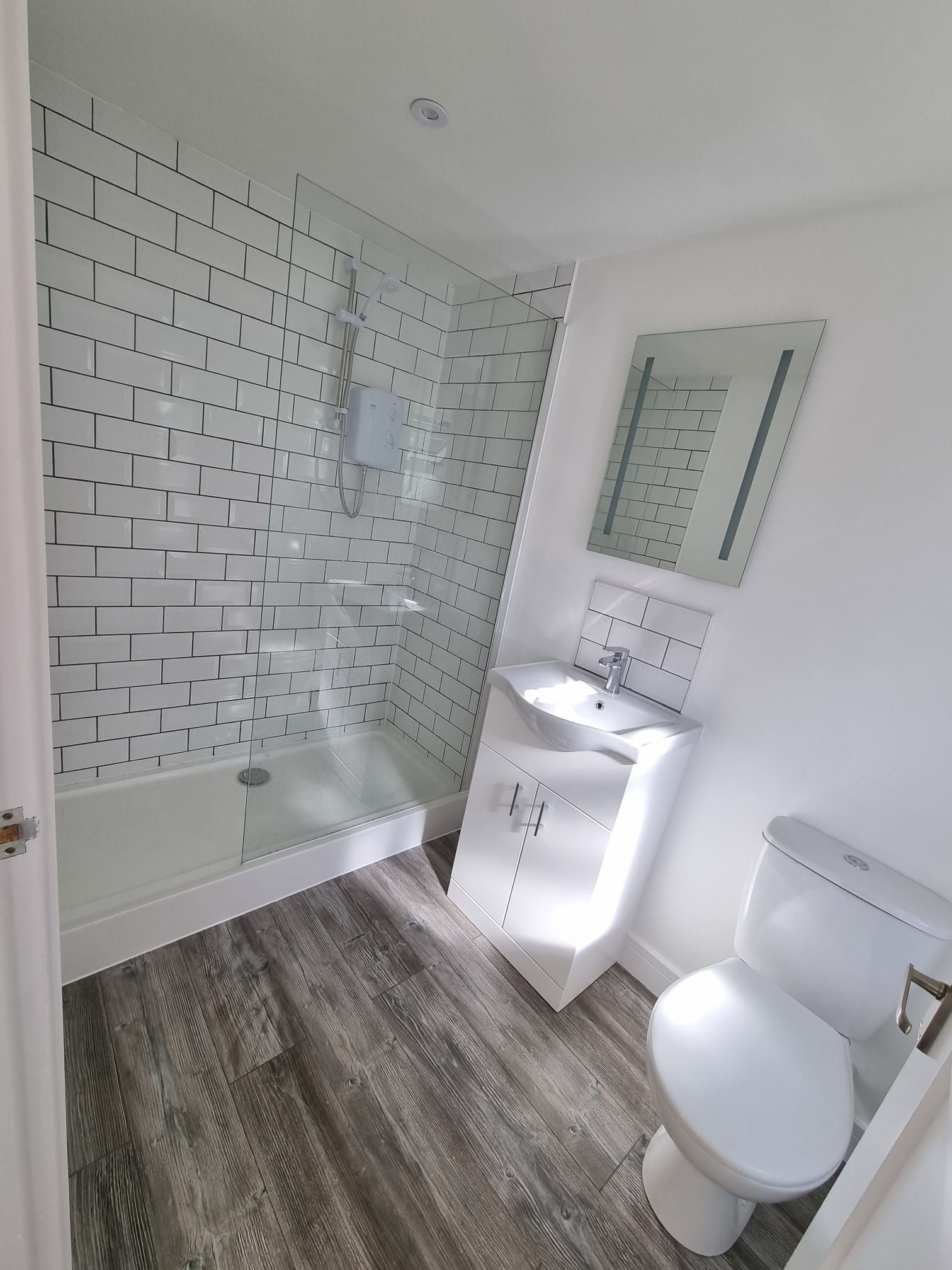 A bathroom with a toilet , sink , shower and mirror.