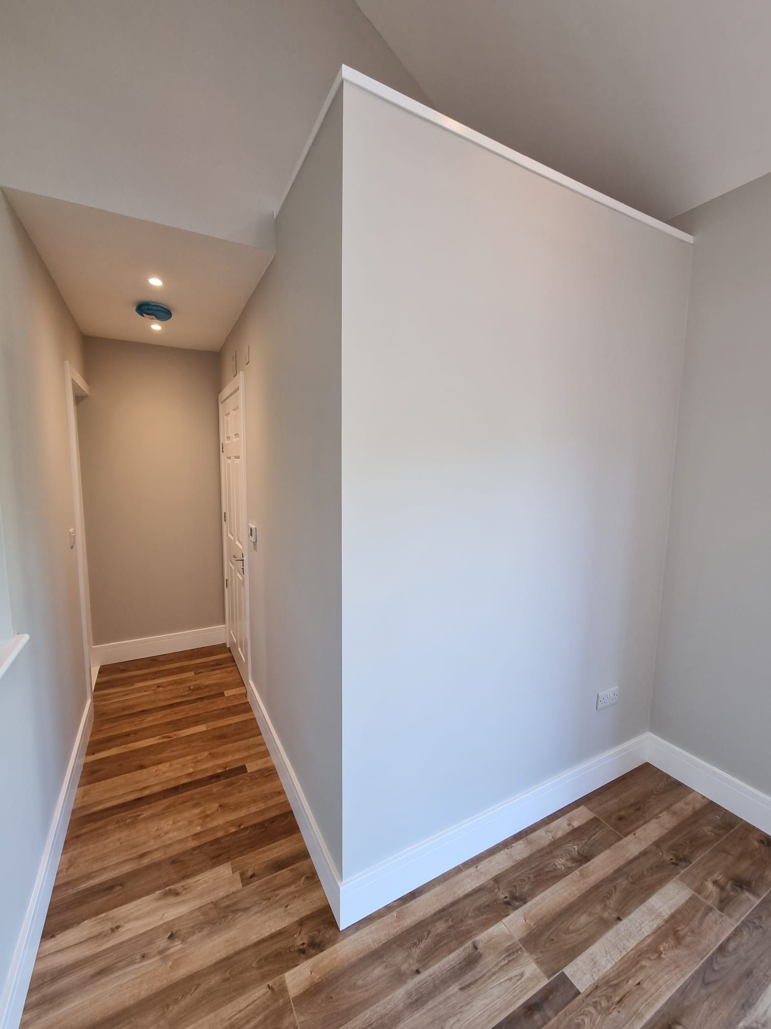 A hallway with wooden floors and white walls in a house.