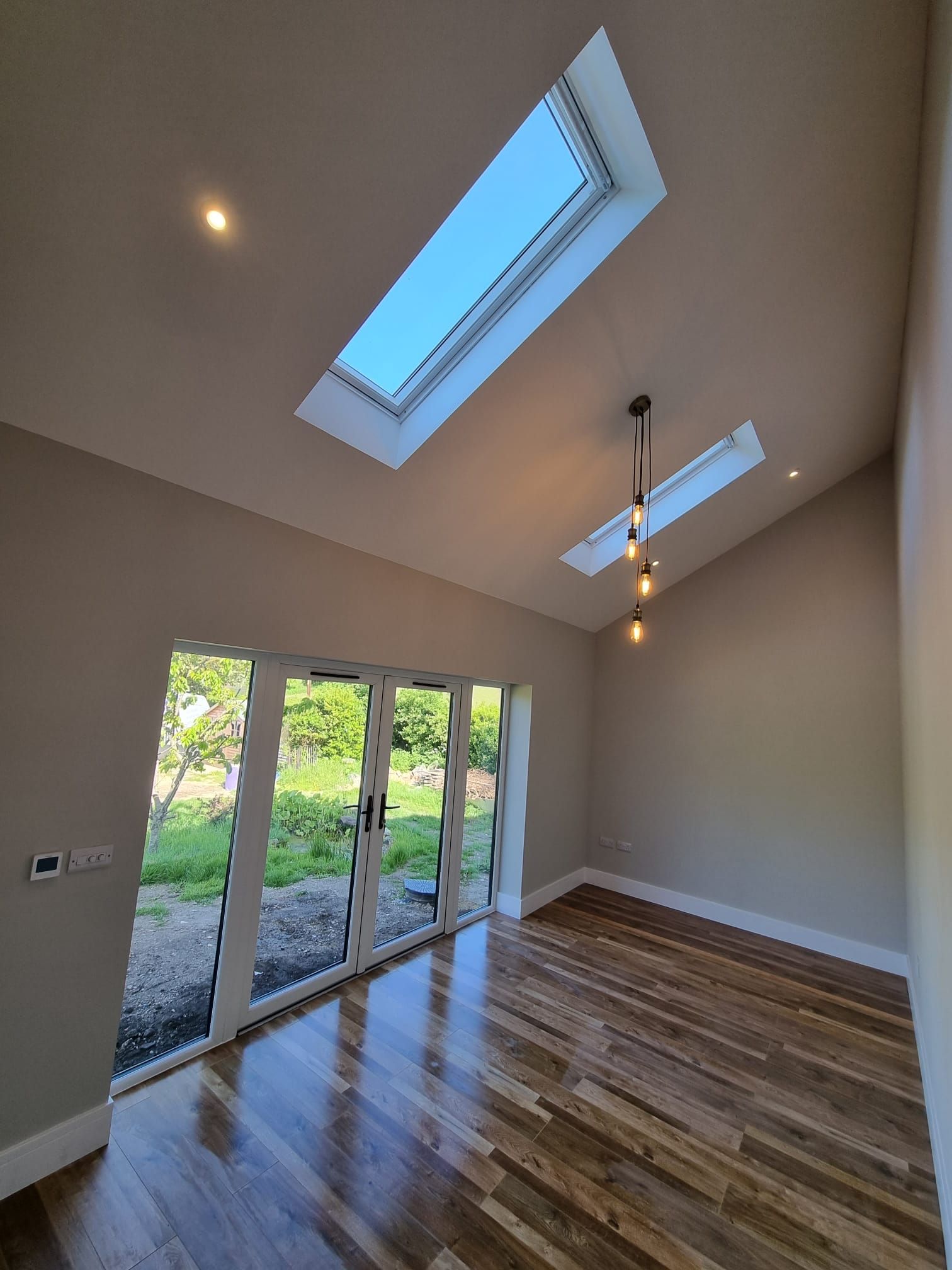 An empty room with a skylight and sliding glass doors