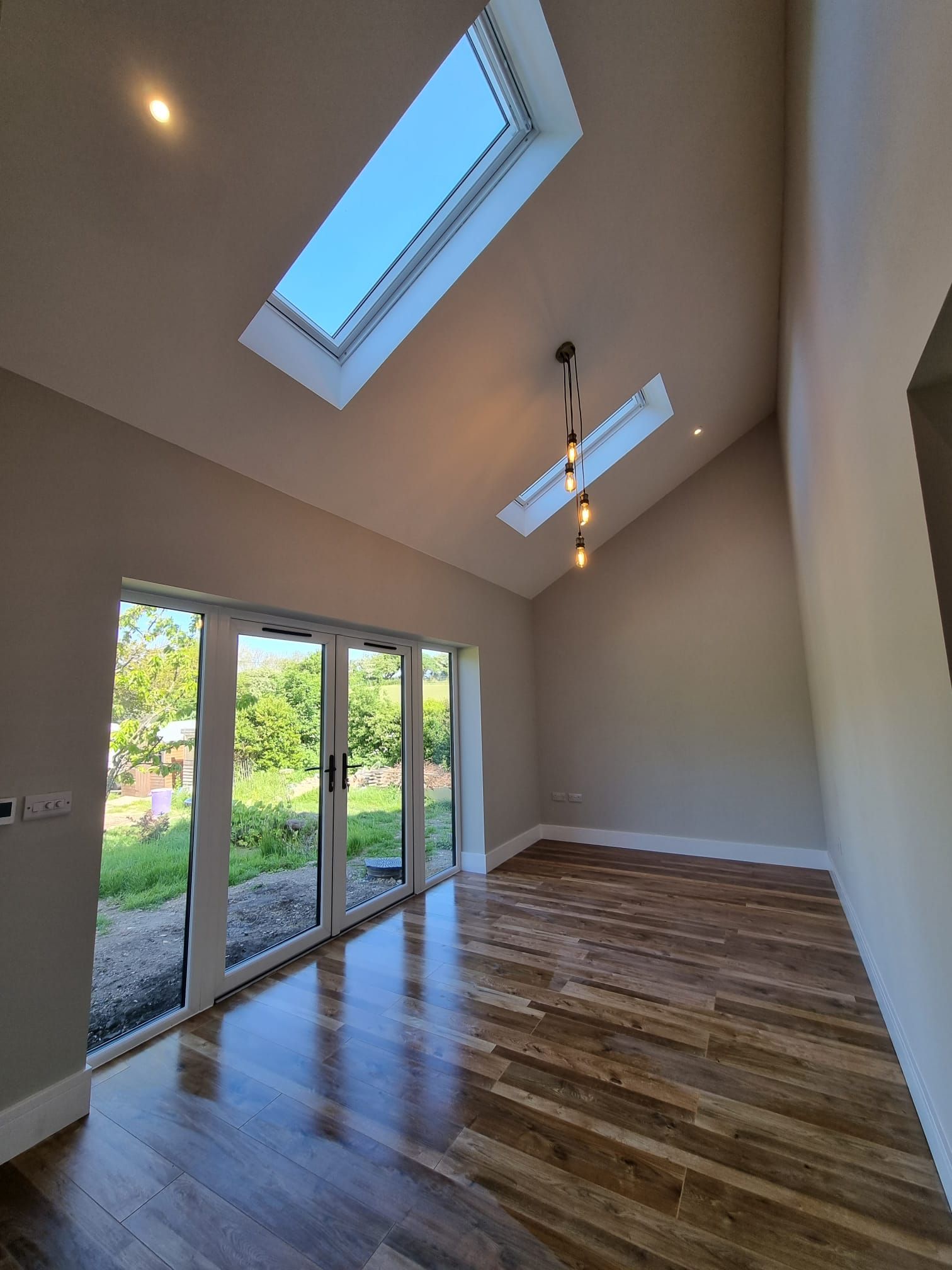 An empty room with a skylight and sliding glass doors